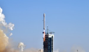 A Long March 2D rocket lifting off from the Jiuquan Satellite Launch Center under clear blue skies, showcasing bright exhaust flames and smoke as it carries the Yuanzheng-3 upper stage and five high-speed laser communication test satellites into orbit.