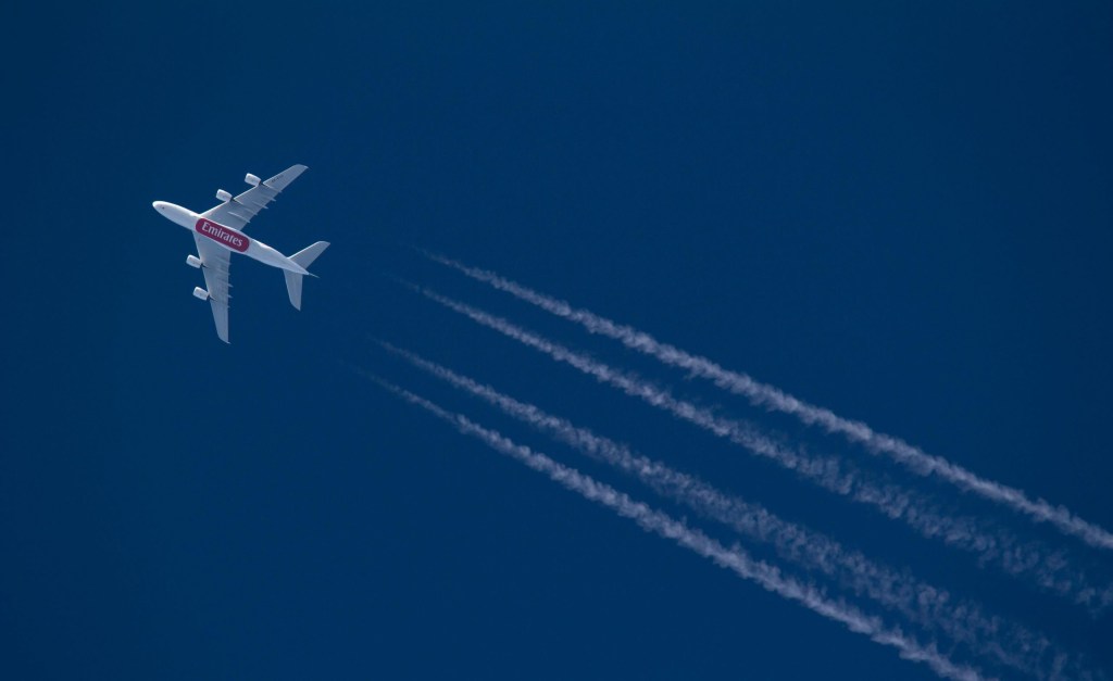 View of a large commercial plane leaving contrails in the sky.