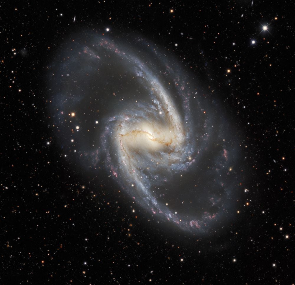 NGC 1365 is also known as the Great Barred Spiral Example. It's a stunning example of its galaxy type. It's about 56 million light-years away in the Fornax Cluster. Researchers have used chemical fingerprints based on oxygen to map out its history. Image Credit: By Dark Energy Survey/DOE/FNAL/DECam/CTIO/NOIRLab/NSF/AURAImage processing: Travis Rector (University of Alaska Anchorage/NSF’s NOIRLab), Jen Miller (Gemini Observatory/NSF’s NOIRLab), Mahdi Zamani & Davide de Martin (NSF’s NOIRLab) - https://noirlab.edu/public/images/iotw2127a/, CC BY 4.0, https://commons.wikimedia.org/w/index.php?curid=107557546