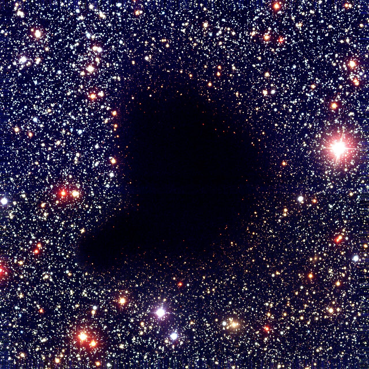 Barnard 68, a dark molecular cloud where dust grains shield the densest interior from UV radiation and catalyze the formation of complex molecules. (CC BY 4.0, ESO)