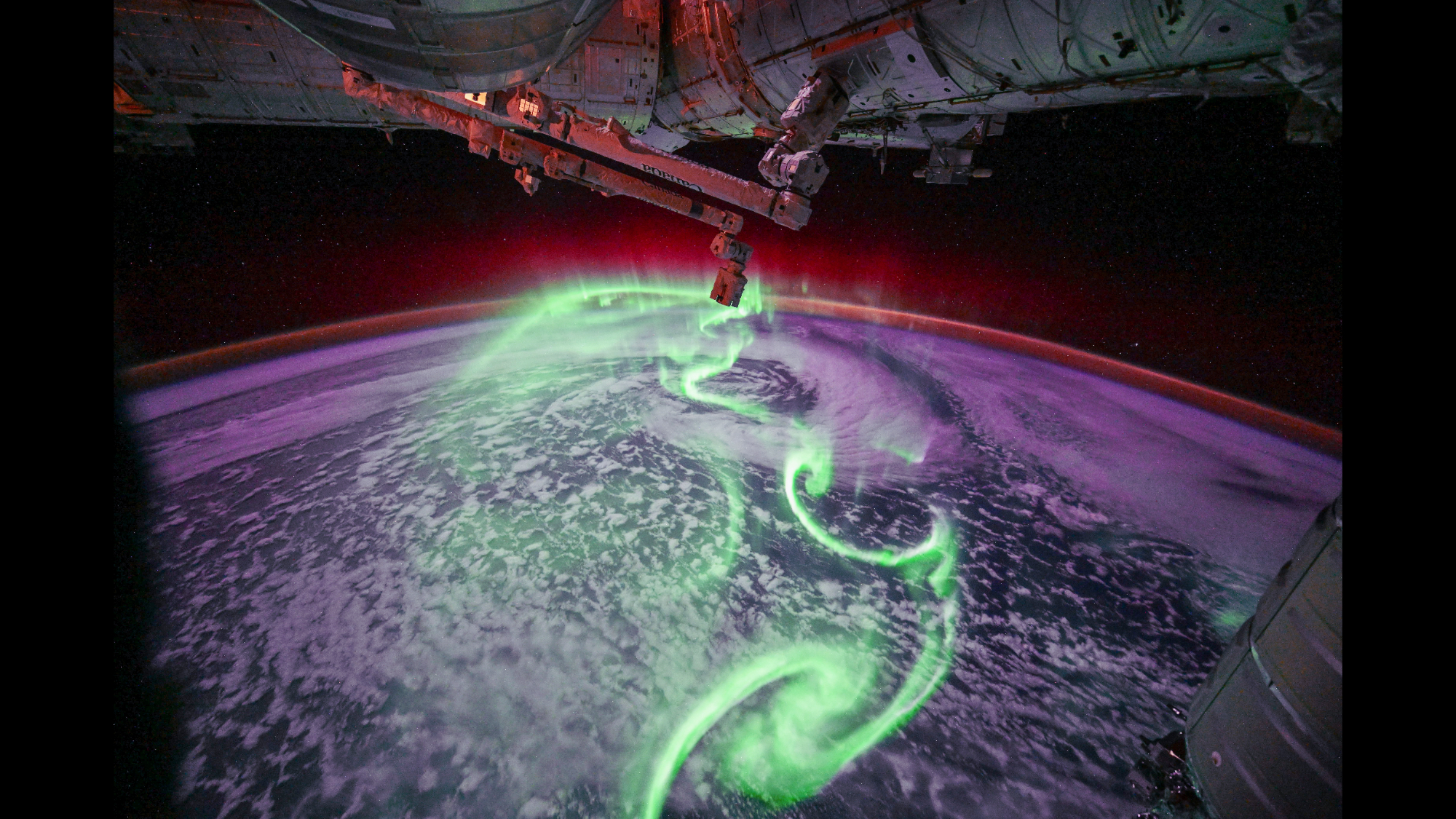 Neon green, purple, and red auroras over Earth.