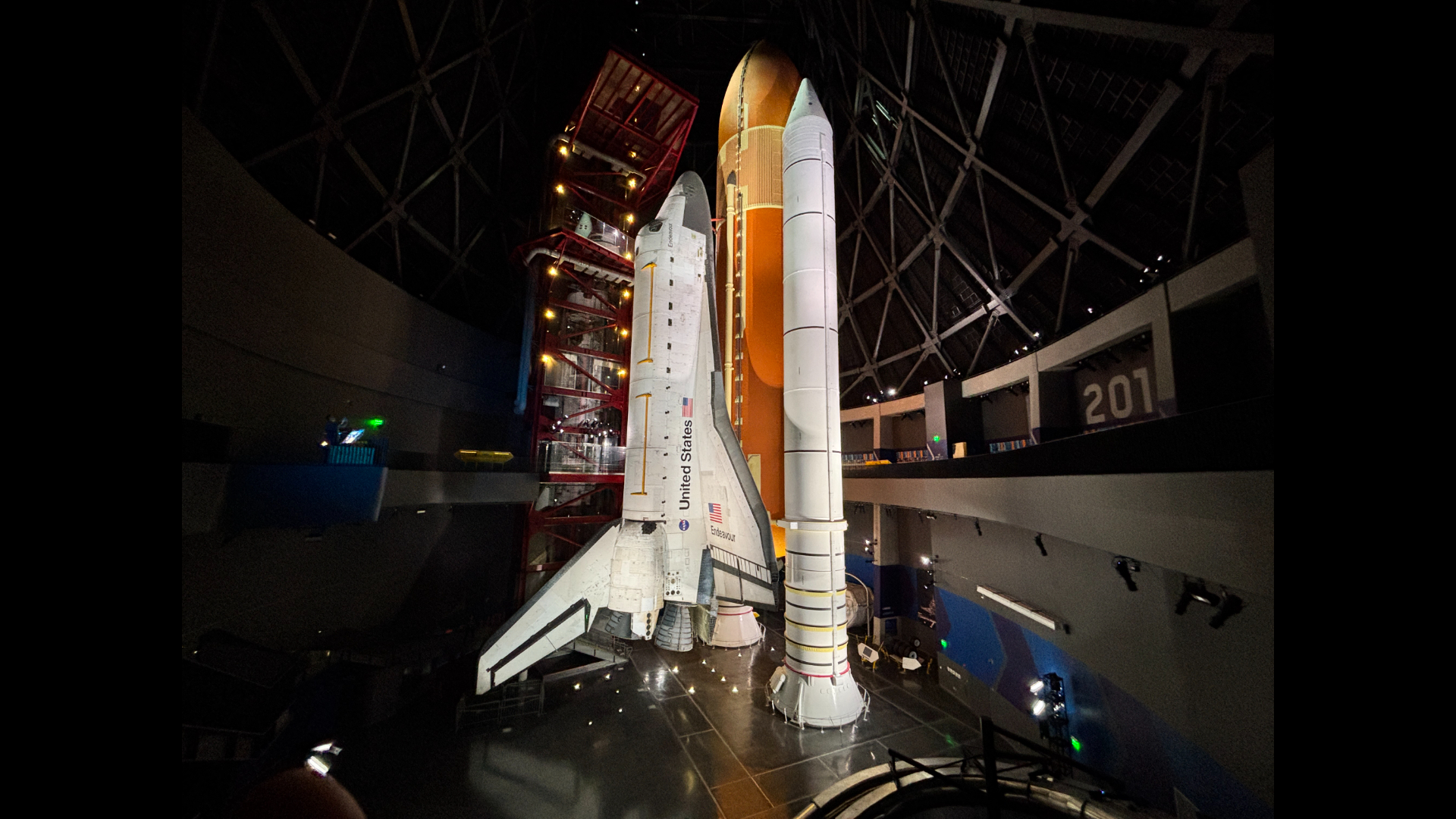 The space shuttle Endeavor stands upright in a museum. 
