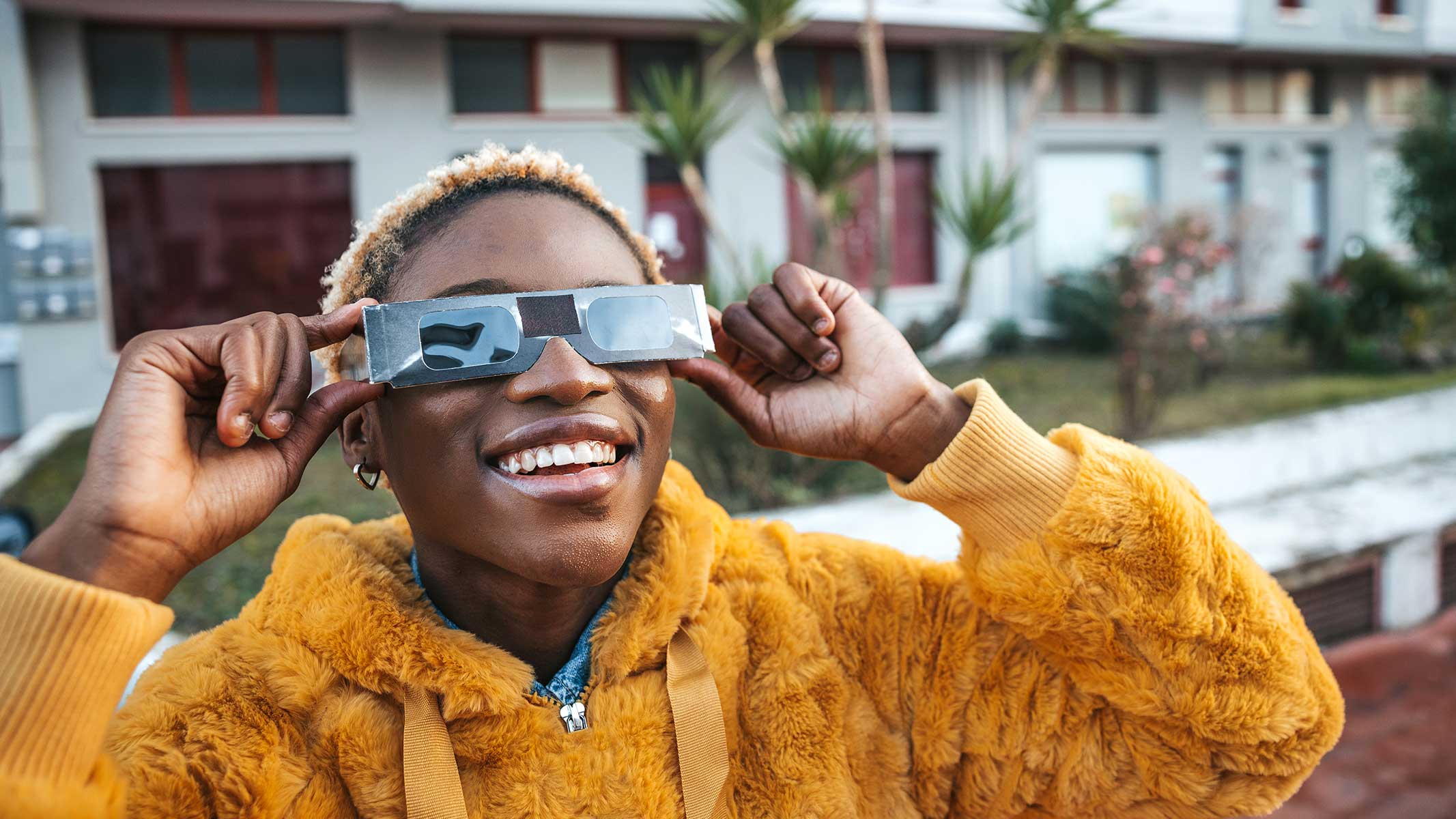 Teenage girl looking at solar eclipse wearing the proper protective eyeglasses