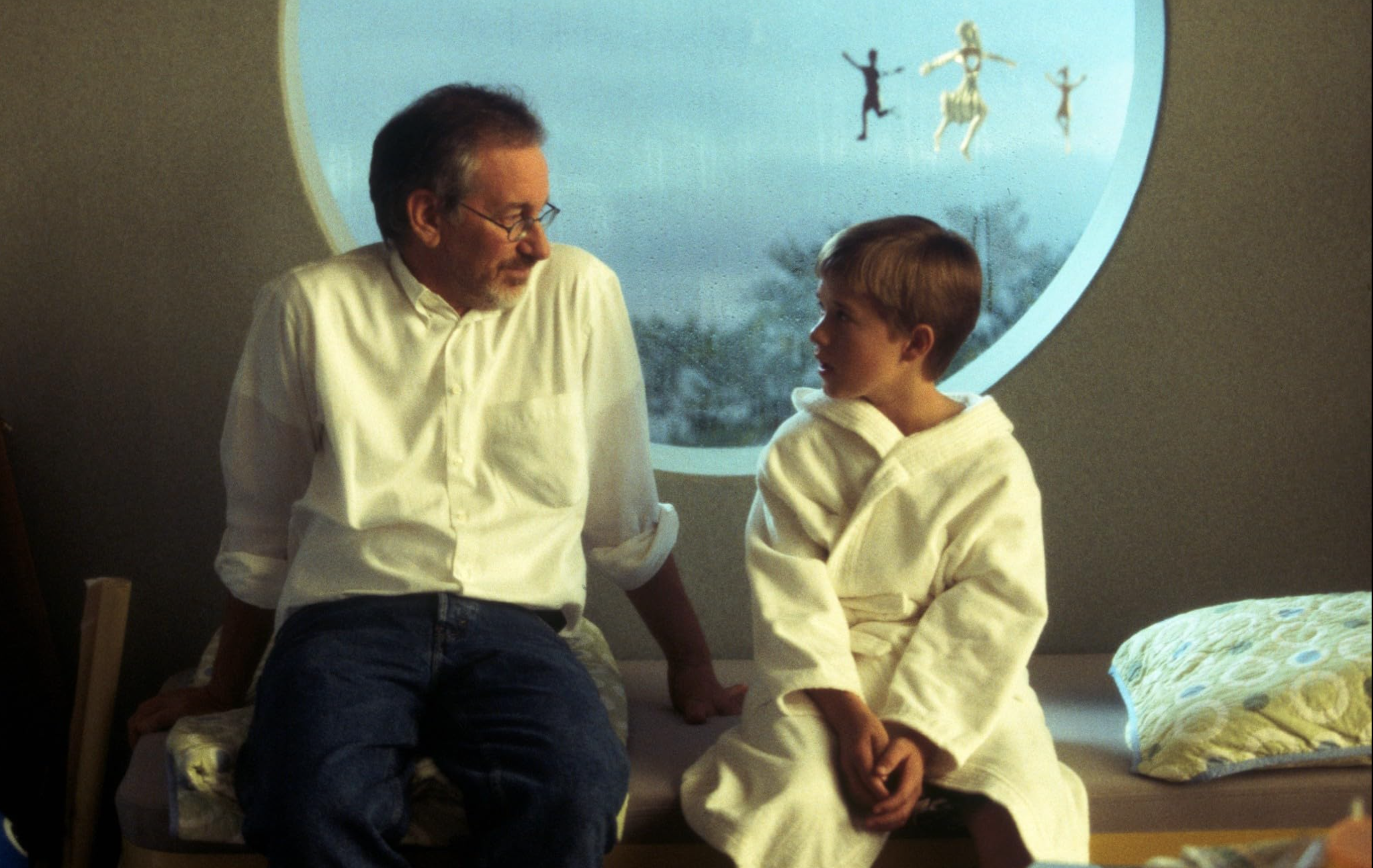 a bearded man sitting with a young boy on a movie set