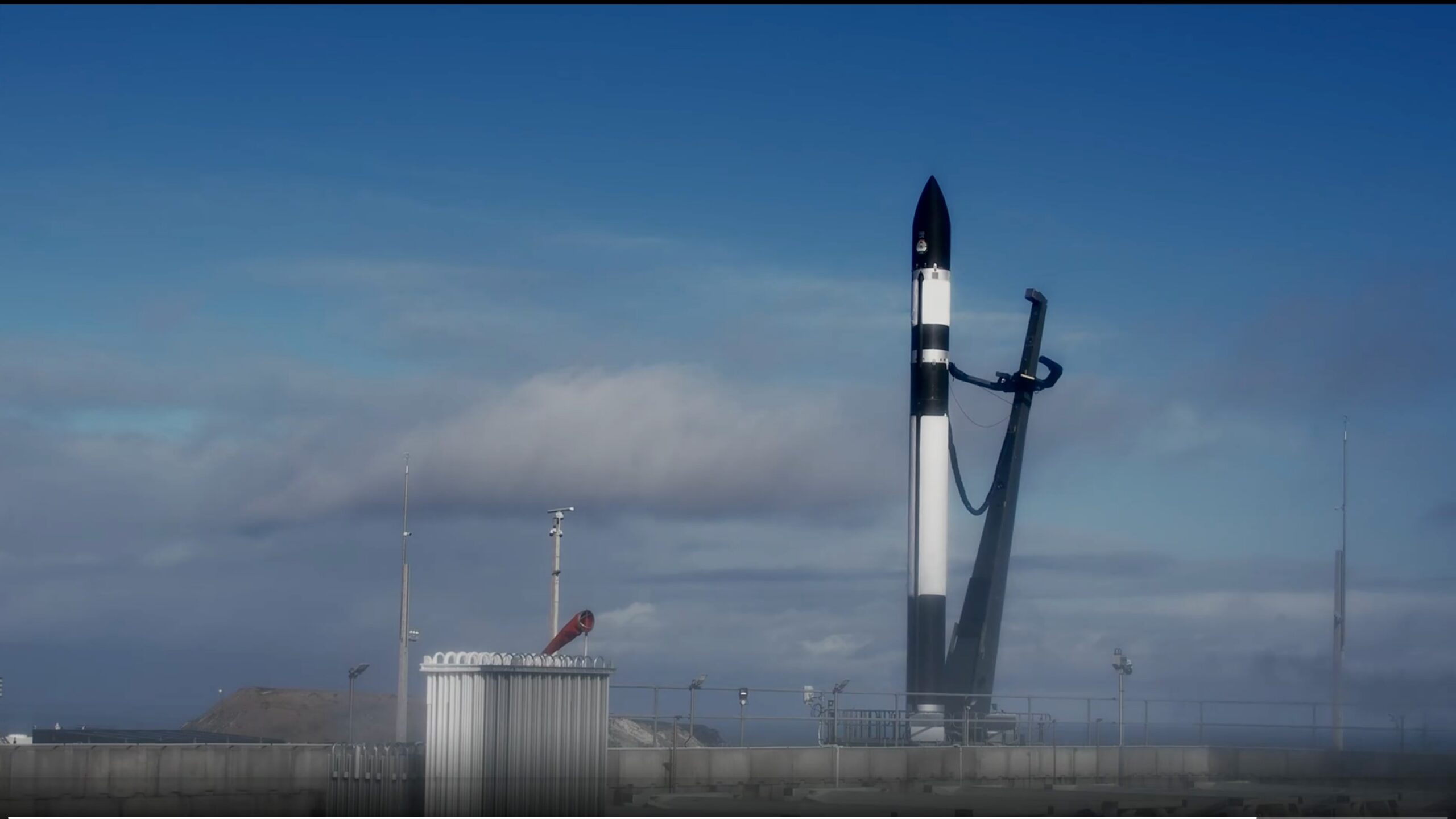 a black and white rocket stands on a launch pad beneath a blue sky