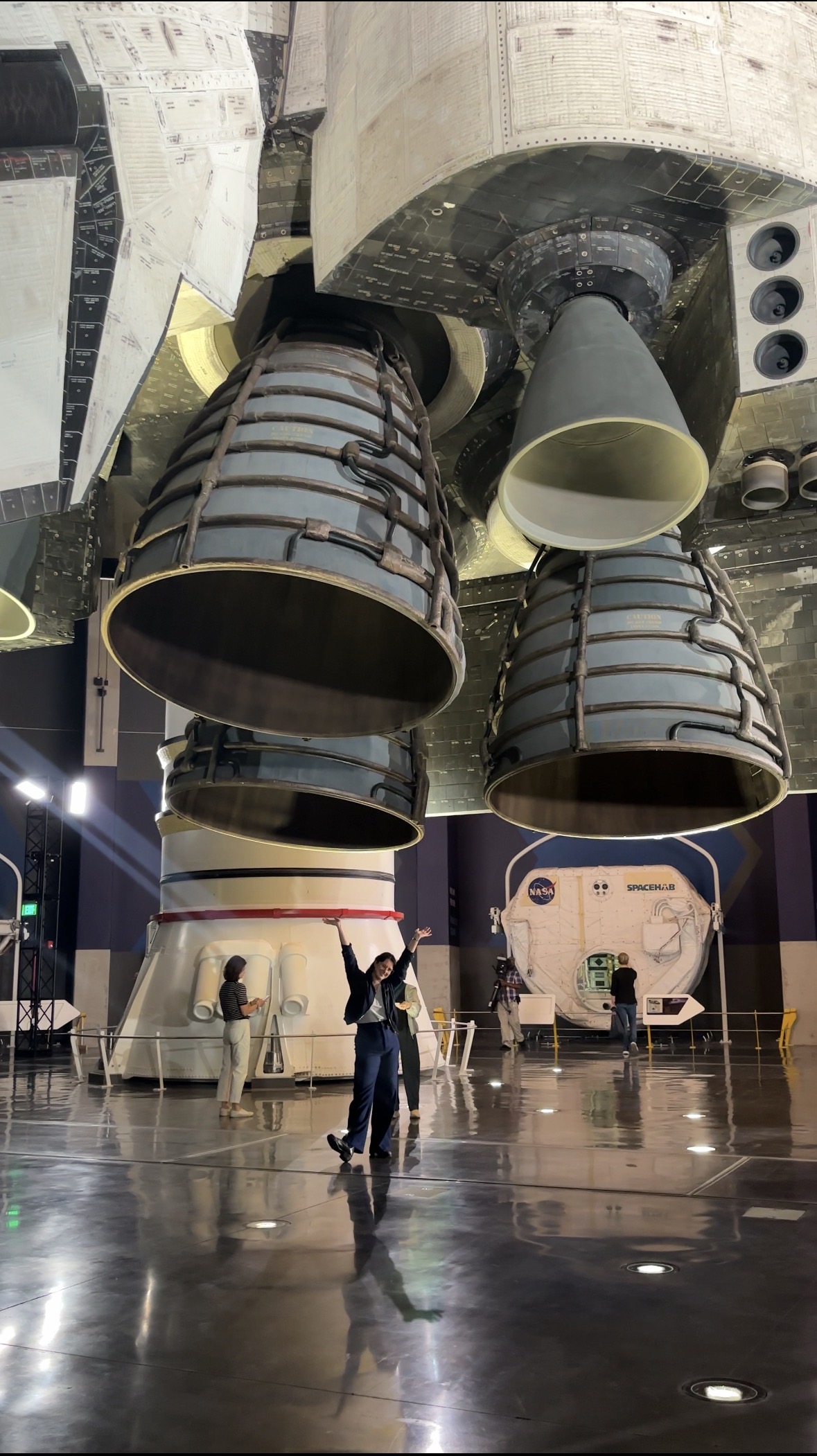 Space.com reporter Chelsea Gohd stands under shuttle engines. 