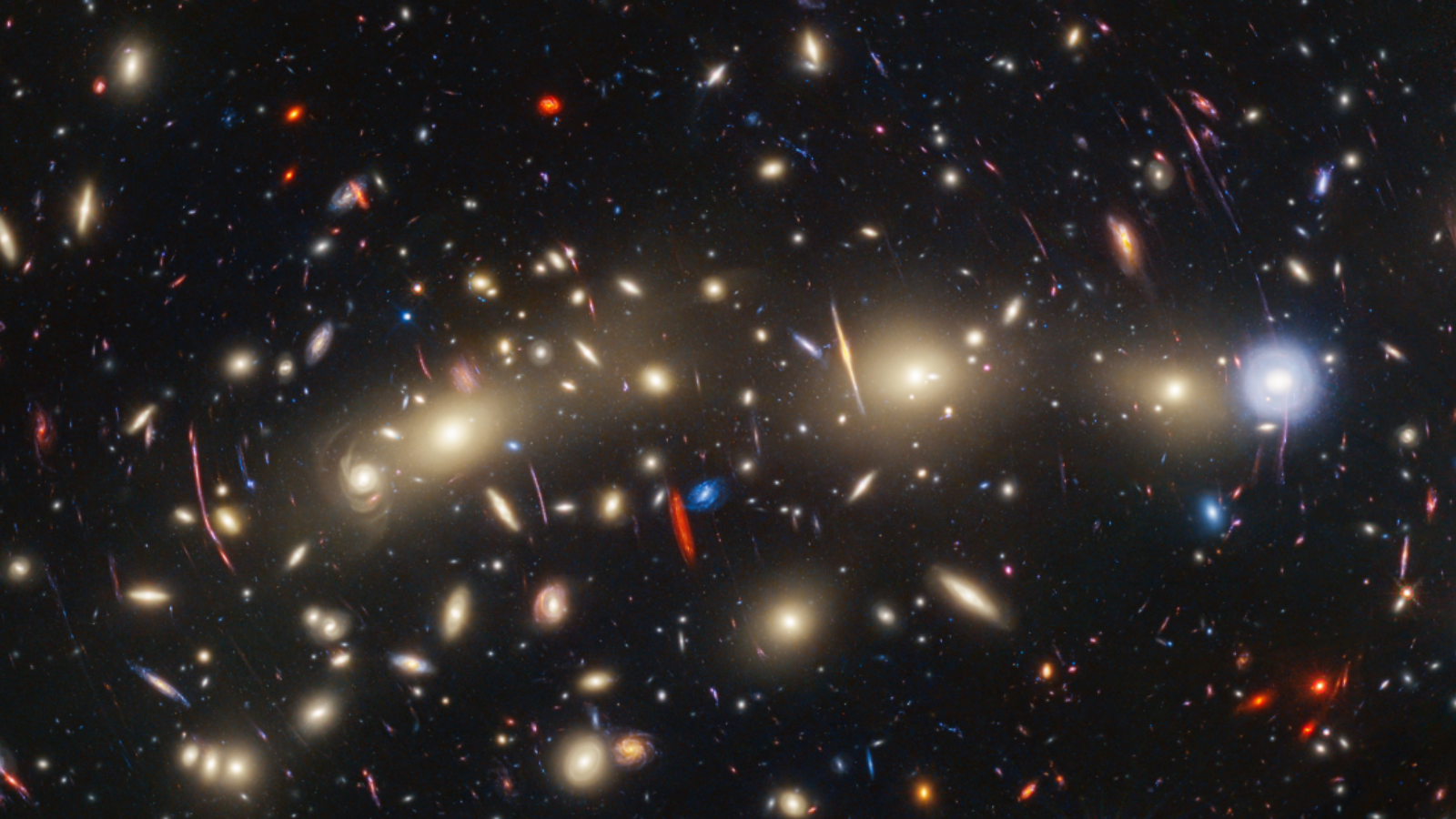 Lots of gravitationally lensed objects in space. They look like different colored dots that are glowing. Some, which are lensed, look more like streaks.