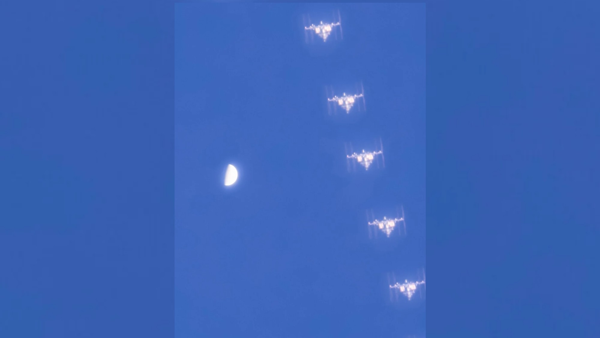 a t-shaped space station next to a white half-orb in a blue sky