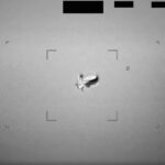 black and white photo of a blurry, football-shaped object in the sky