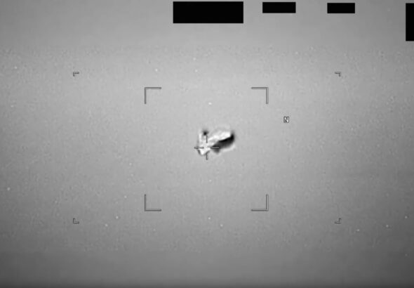 black and white photo of a blurry, football-shaped object in the sky