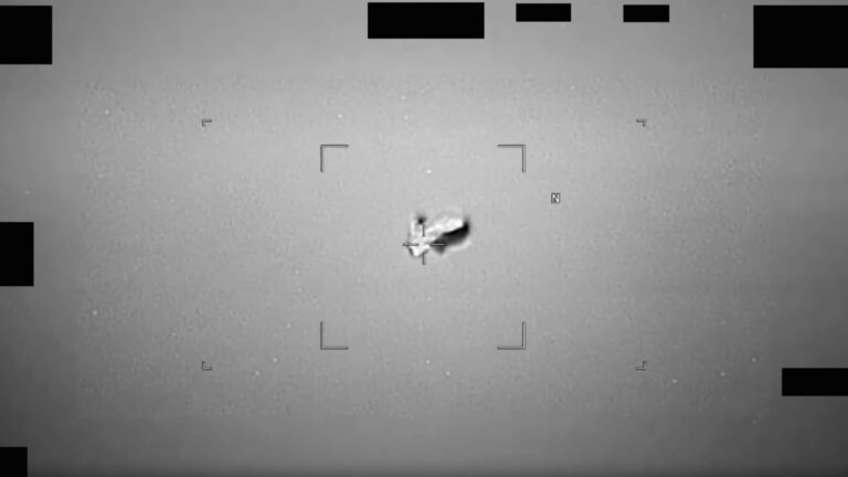 black and white photo of a blurry, football-shaped object in the sky