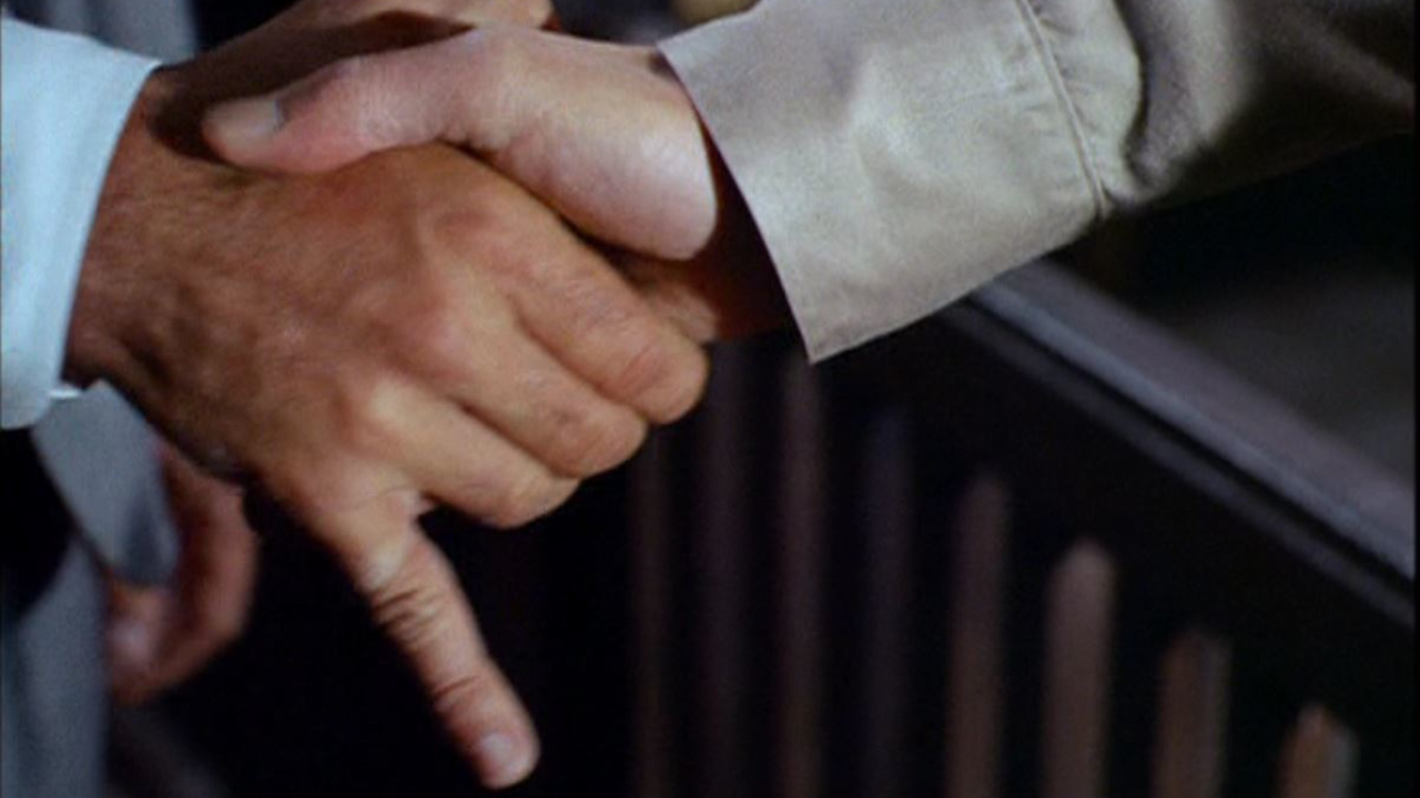 A handshake, with one person's pinky finger extended