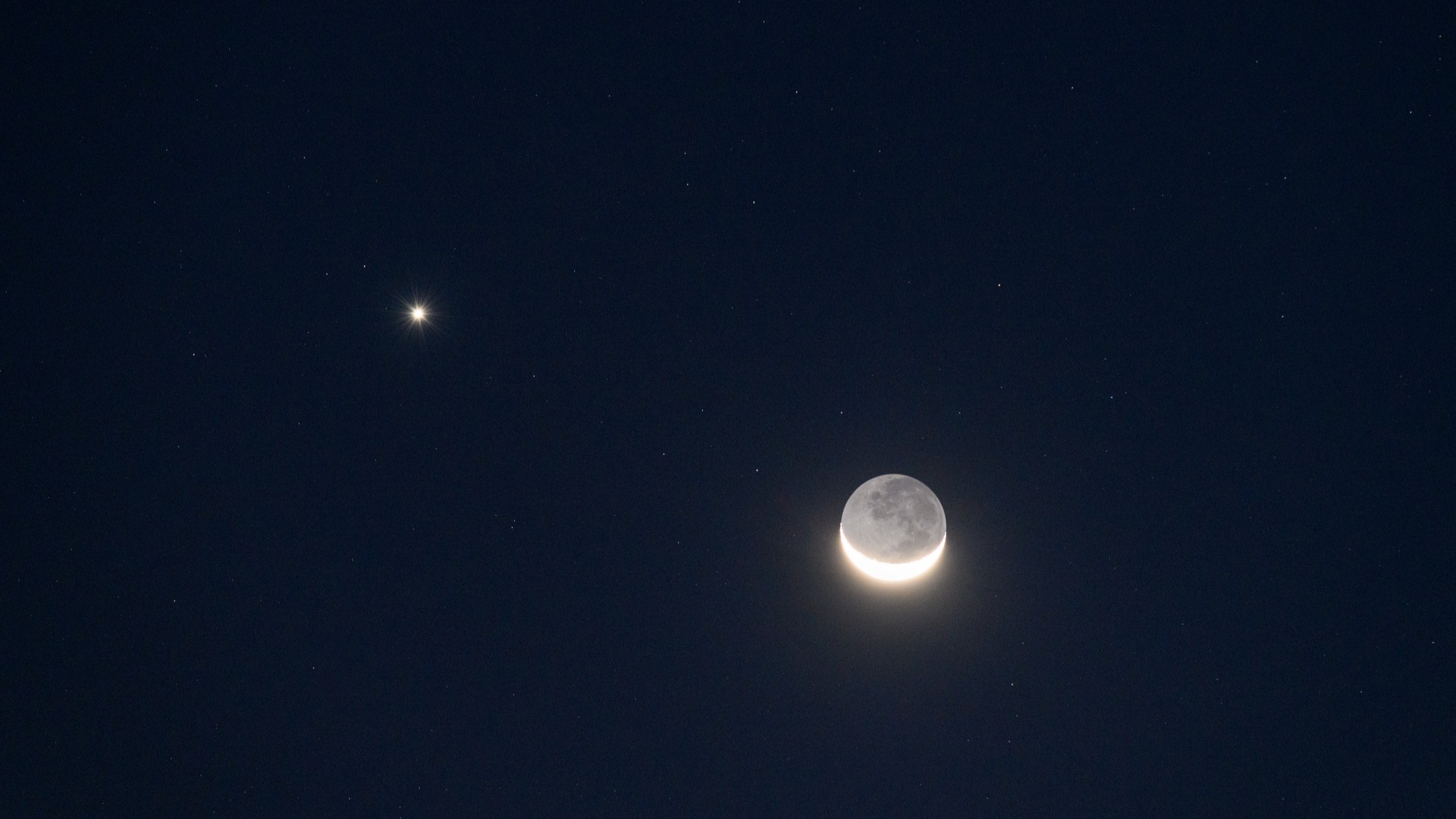 a bright point of light on the left is venus with a crescent moon with earthshine on the right.