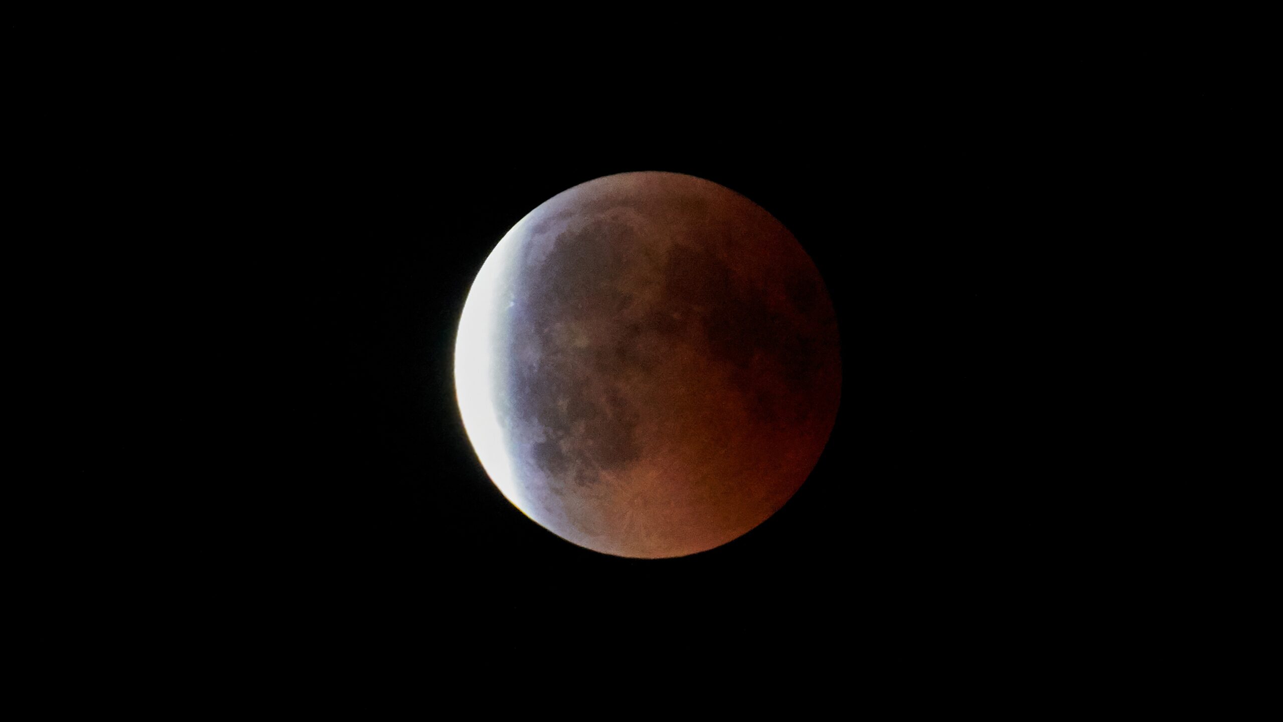 a dark red moon on the left is a sliver of light