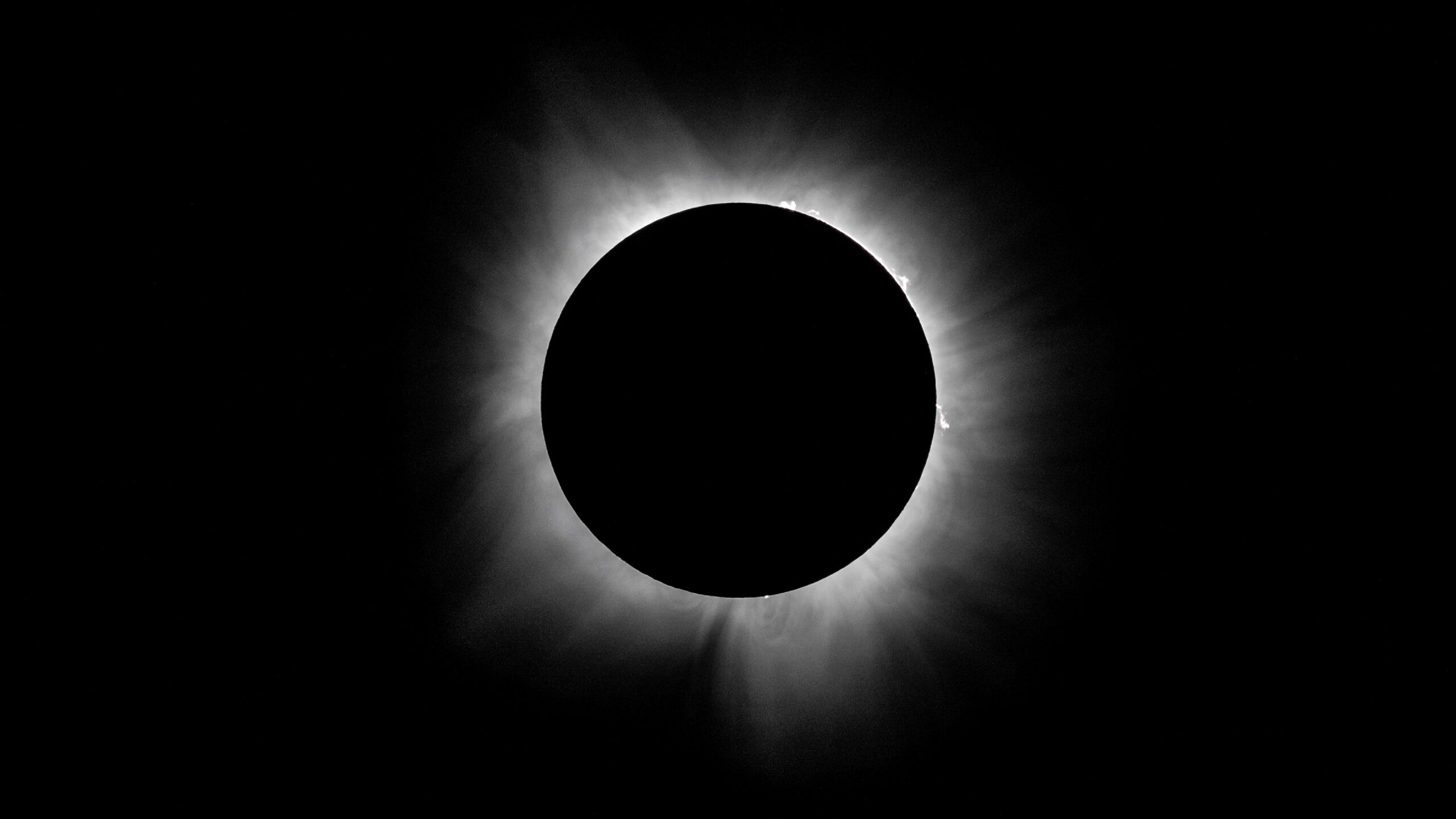 The sun's corona shines from behind the lunar disk in a black sky at totality during the 2024 eclipse.