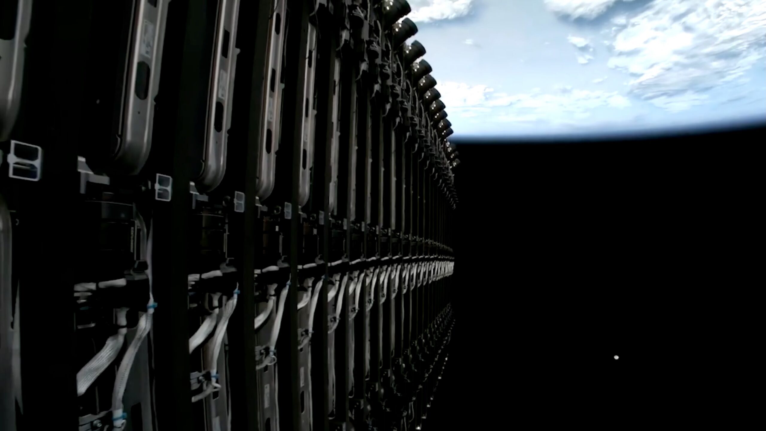 a stack of folded-up satellites is seen high above earth, still attached to their rocket