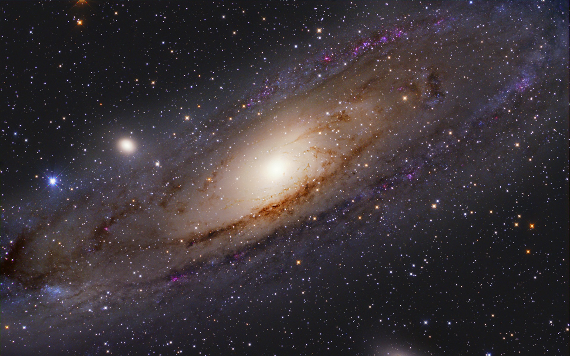 A spiral galaxy with lots of stars in the background. A bright haze is seen coming from the center of the galaxy. Toward the center left there is a glowing dot. And on the center right another glowing dot mostly offscreen.