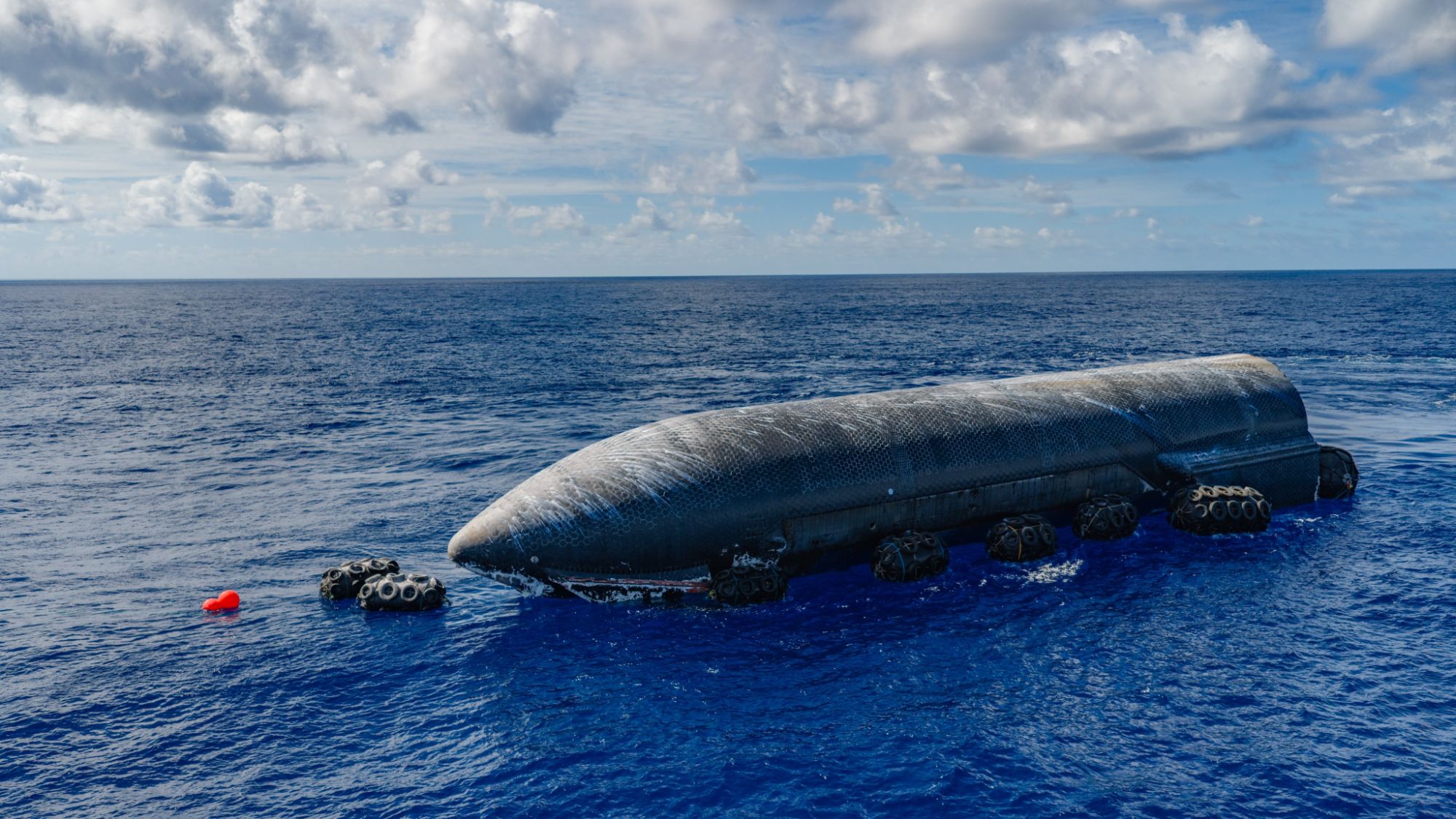 A giant dark rocket floats in the blue ocean.