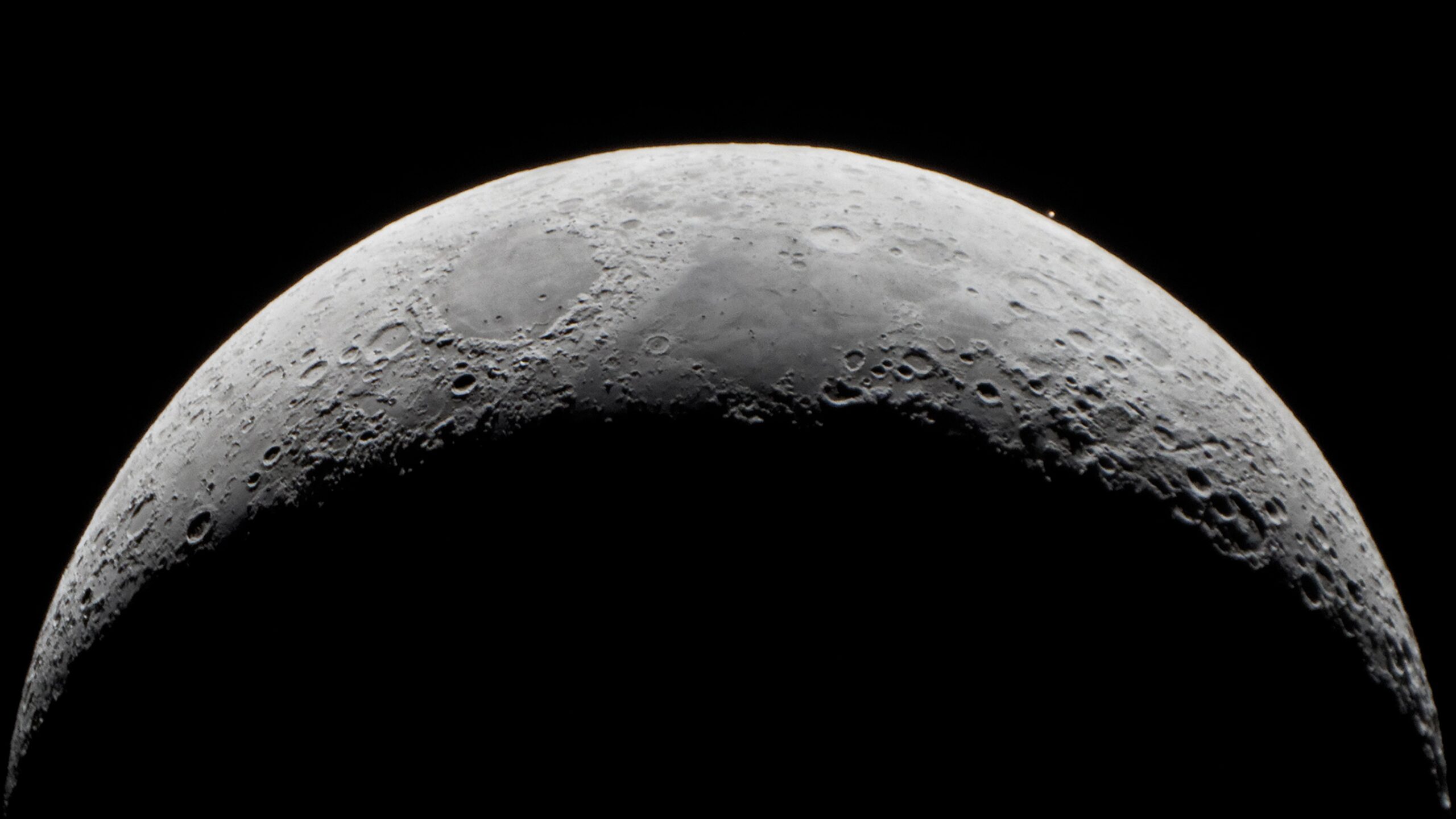 close up view of the moon and toward the upper right of the moon a tiny dot of rusty red light - Mars