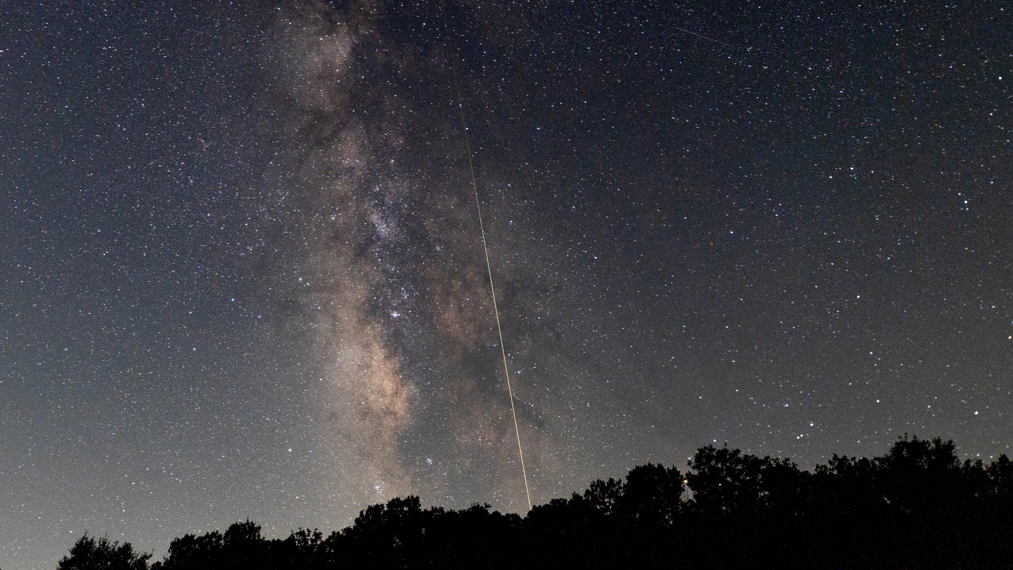 a streak of light crosses through the night sky