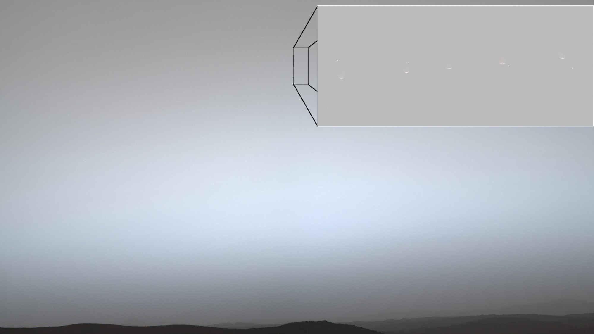 a dot of light disappears behind a crescent of light on a grey background