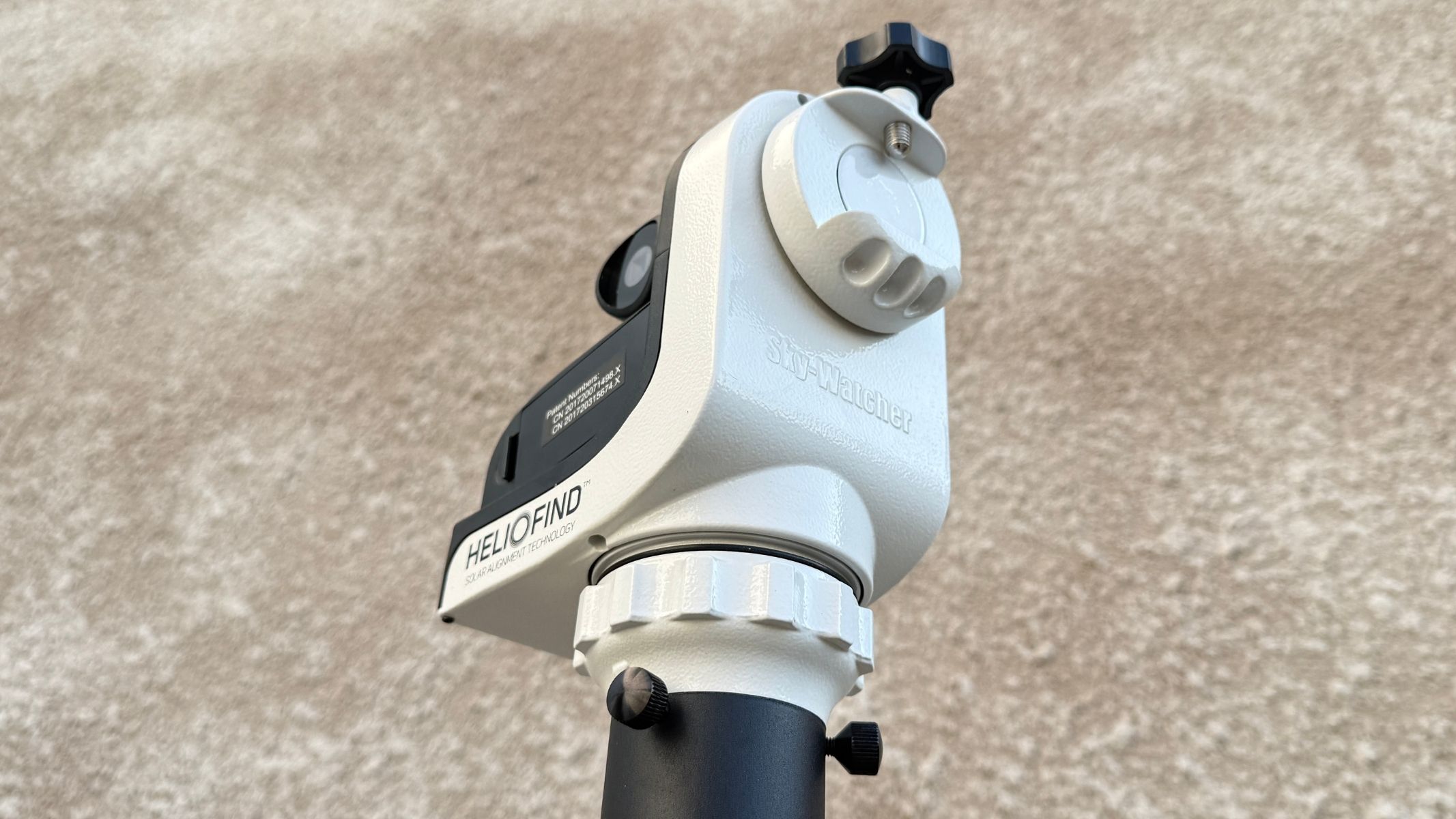 A close-up of the Sky-Watcher SolarQuest solar telescope mount, showing the telescope attachment, against a white textured wall.