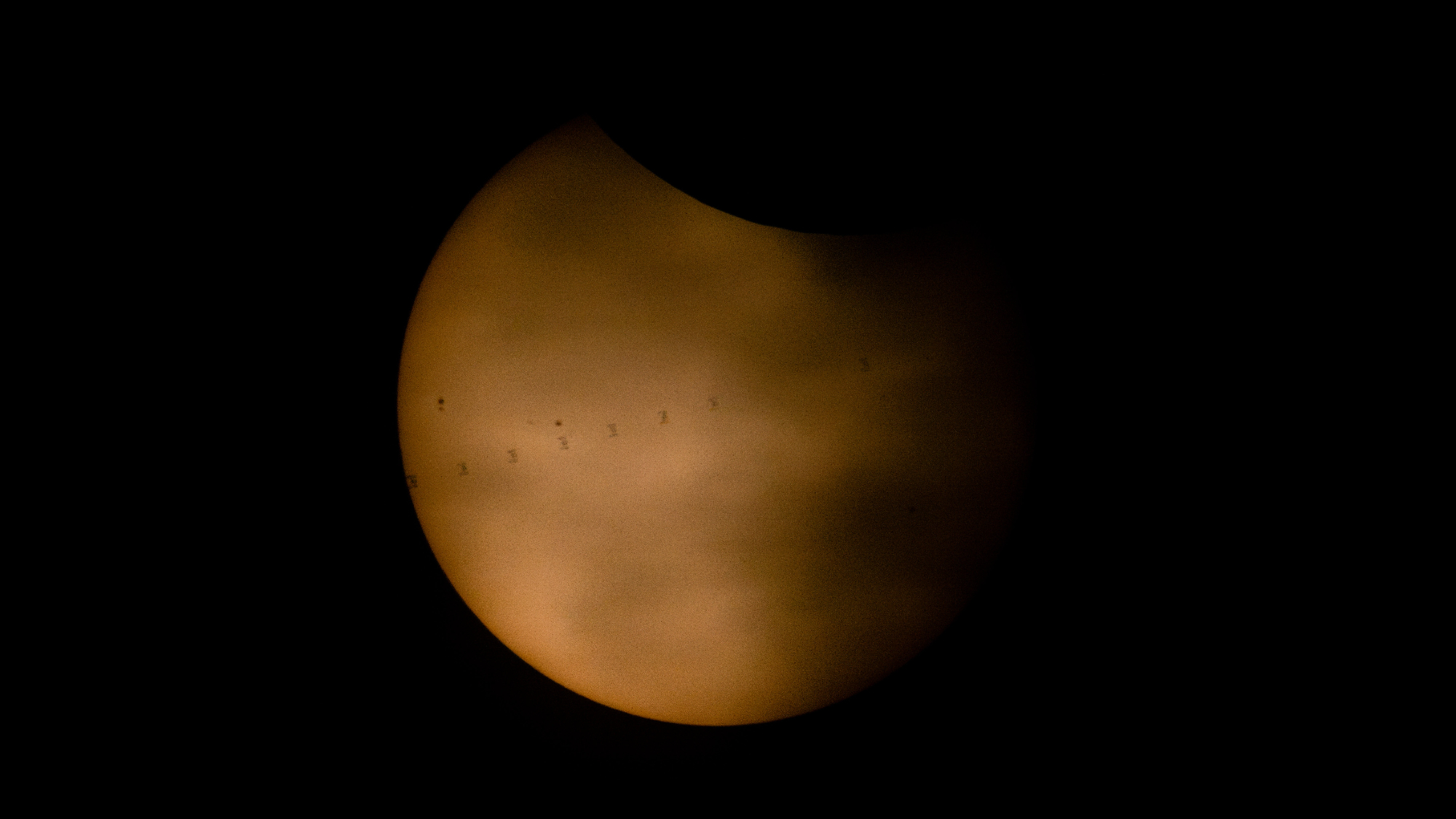 The silhouette of the ISS transiting across the sun's face.