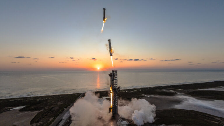 a large silver rocket comes in for a landing on its launch pad near the sea