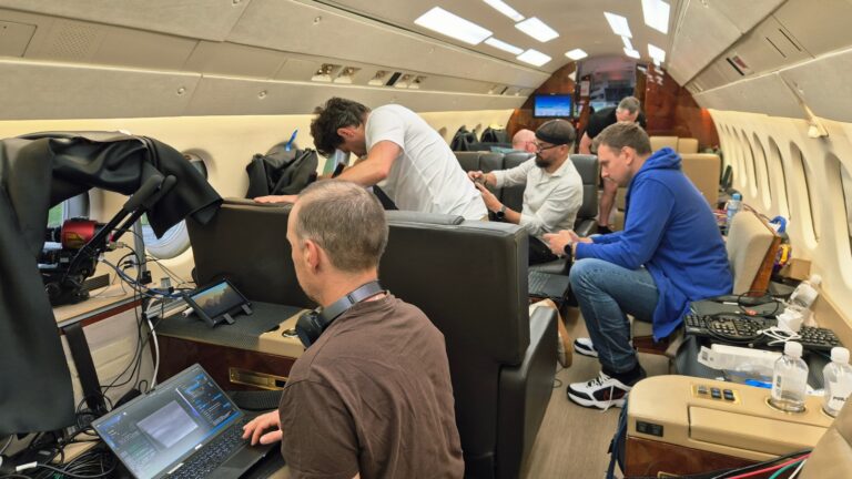six people inside a private jet, with computer equipment strewn around the cabin
