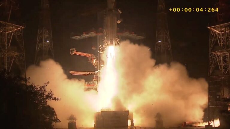 a white rocket launches into a dark night sky