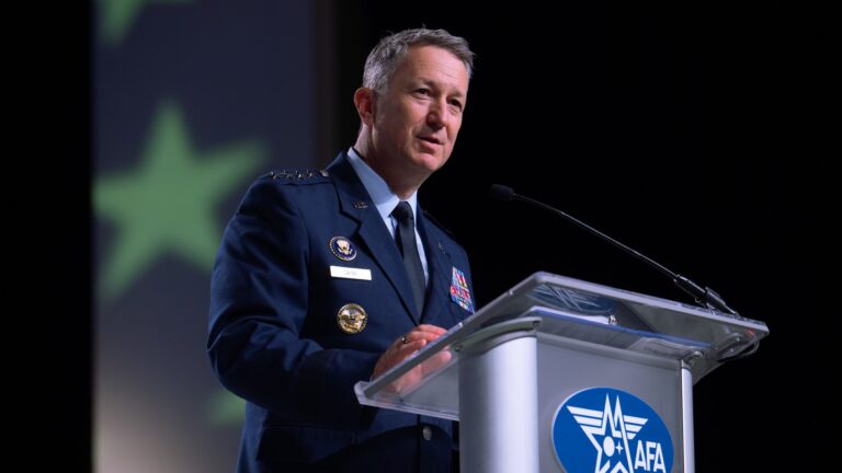 a military man in a blue uniform speaks at a silver lectern