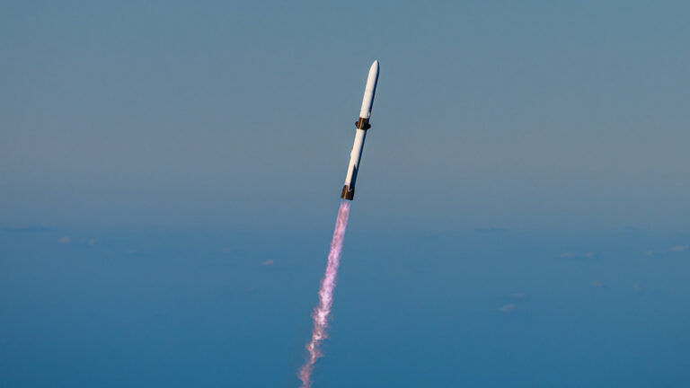 a large white rocket flies through a blue sky