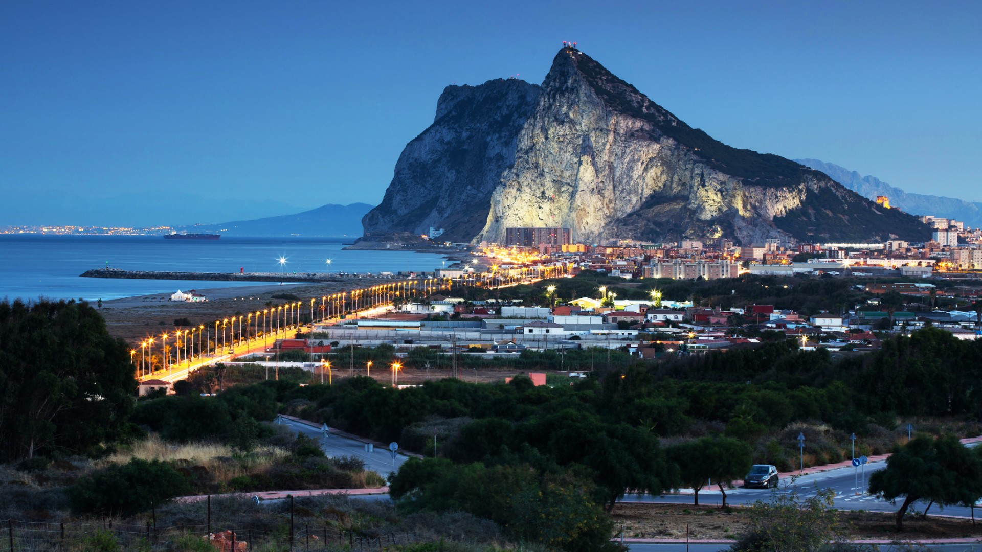The giant Rock of Gibraltar towers over the night-time lit city.