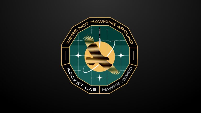 a circular mission patch featuring a hawk in front of a yellow sun with the words "We're Not Hawking Around" around the patch's border