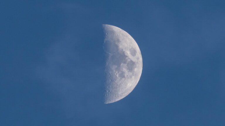 a half illuminated moon in a daytime sky.