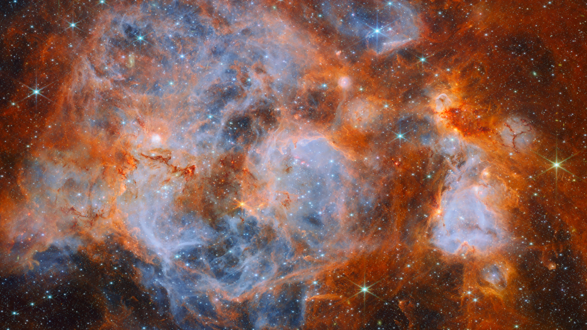 A swirling deep space nebula vista reveals pockets of pale blue glowing gas surrounded by reddish-orange clouds peppered with stars.