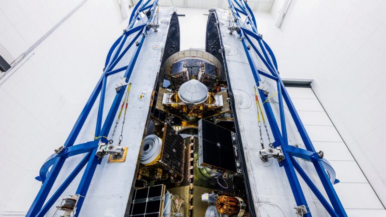 photo of a stack of satellites being processed for launch inside a large white clean room