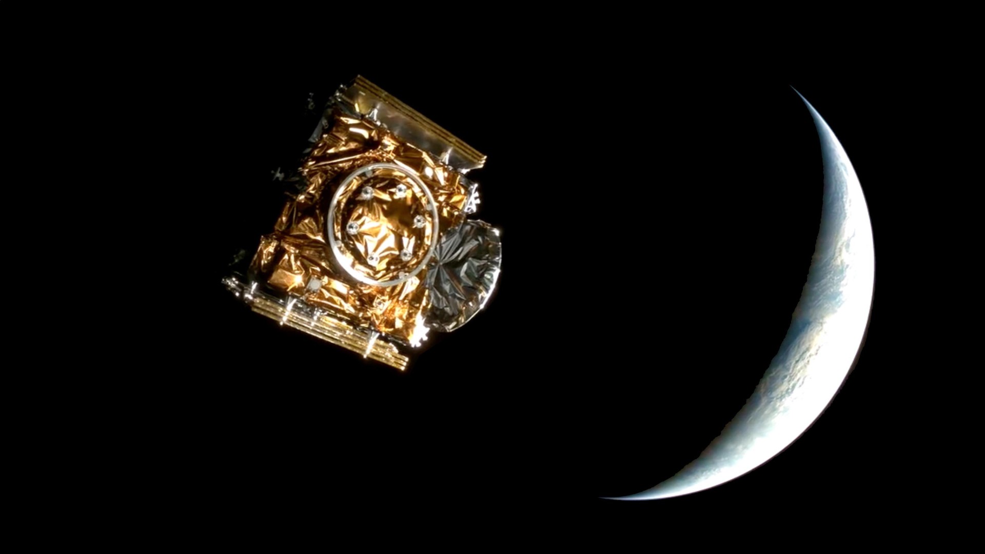 a cube-shaped spacecraft wrapped in foil floats on a black background