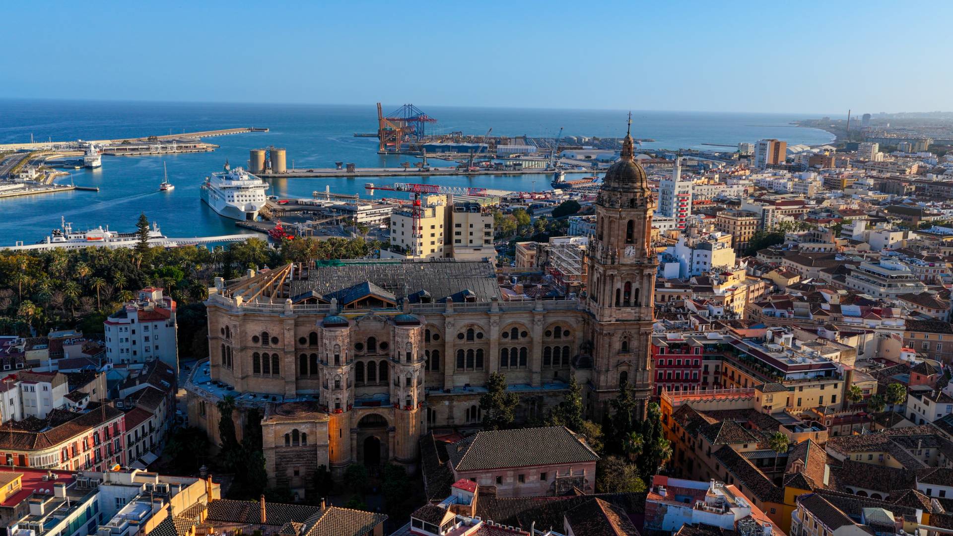 Aerial view of the giant M&amp;aacute;laga Cathedral and historic dense city center at sunset. In the distance you can see the palm tree-lined harbour.